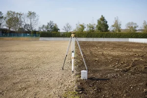 隣接する土地の境目に置かれた測量機器と境界標